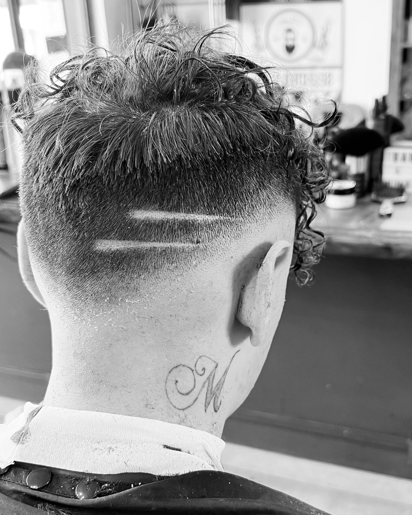 Taglio creativo con riccioli e skin fade visto da dietro